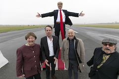 Querformat: Hannes Heesch, etwas erhöht, als Donald Trump im Anzug. Er breitet die Arme aus. Vor ihm, etwas tiefer, stehen Christoph Jungmann, Bov Bjerg, Horst Evers und Manfred Maurenbrecher und schreien ihre Verzweiflung heraus.